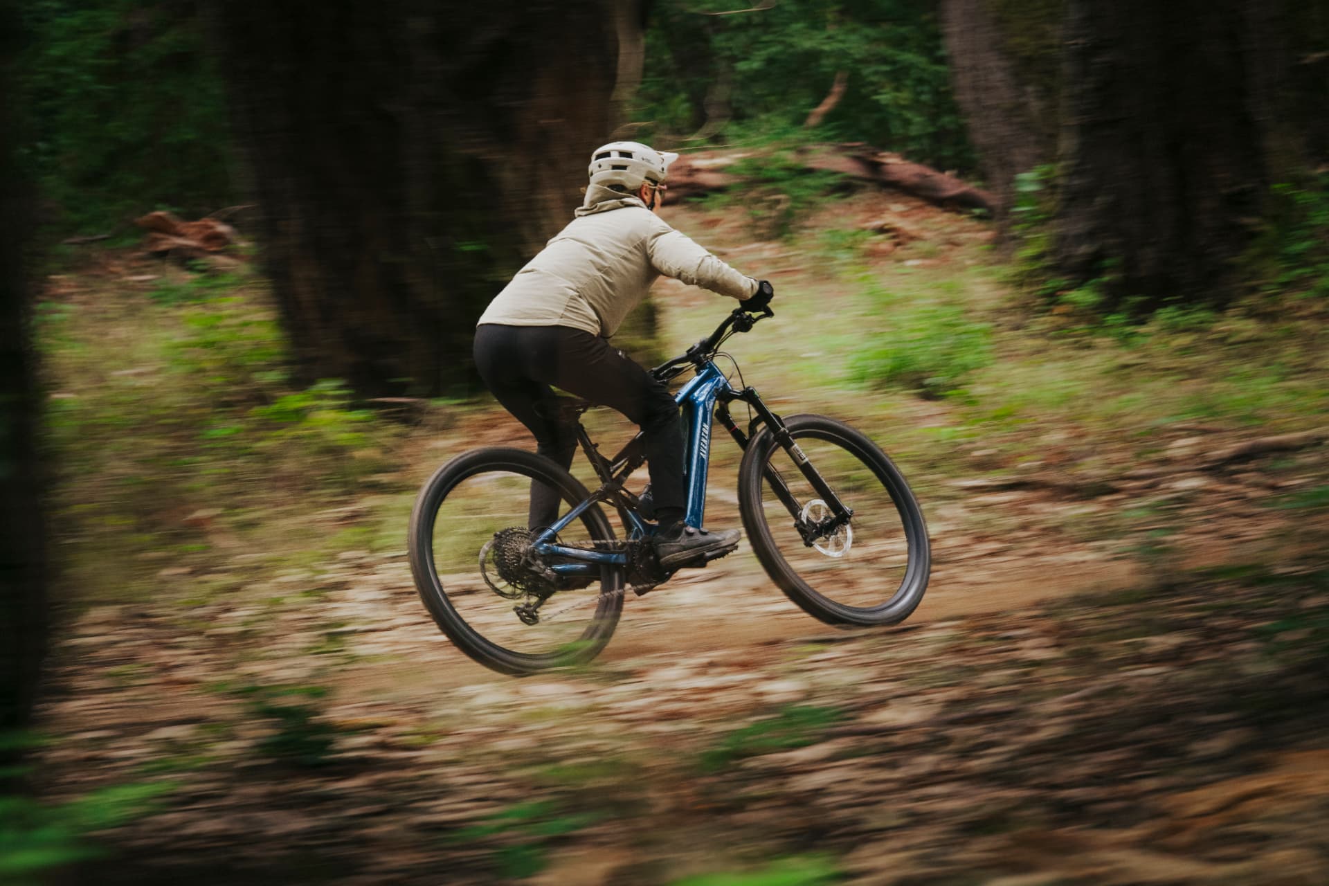 Ciclista saltando en un sendero de bosque sobre una bicicleta eléctrica Aventon